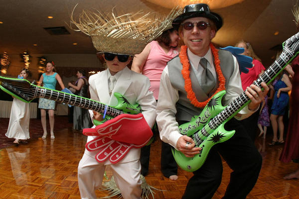 Boy and father dancing in costumes with blow up guitar props
