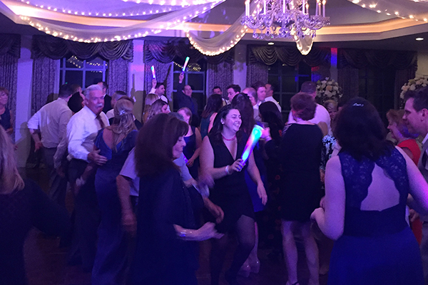 Wedding guests dancing on dance floor with glow sticks and lights