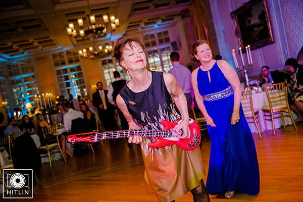 Women at wedding dancing with blow up guitar on dance floor